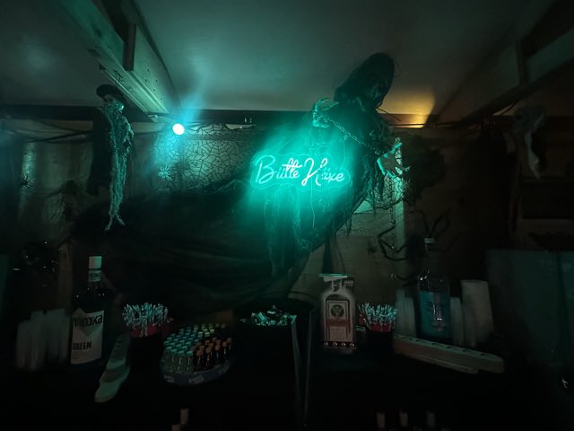 Bar im Häxechessel mit türkis leuchtendem Vereinsschriftzug und Flaschenregal