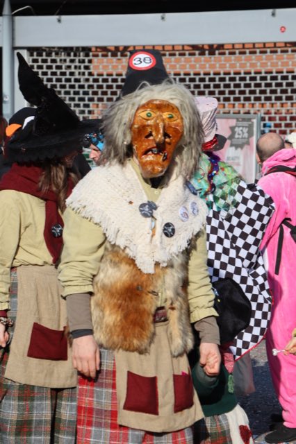 Häx mit geschnitzter Maske und weissem Fellkragen im Umzug