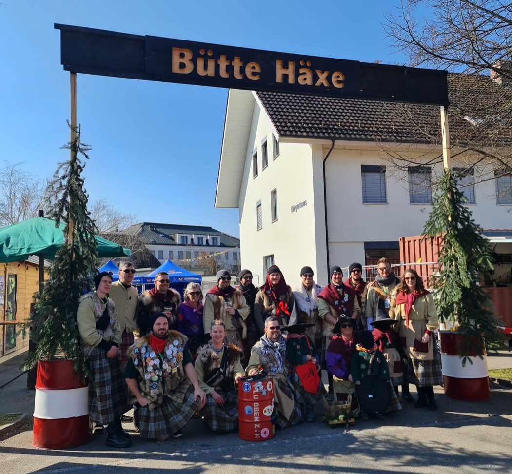 Die Bütte Häxe in Fellwesten und Karoröcken stehen unter ihrem hölzernen Vereinsschild beim Bürgerhaus Möhlin