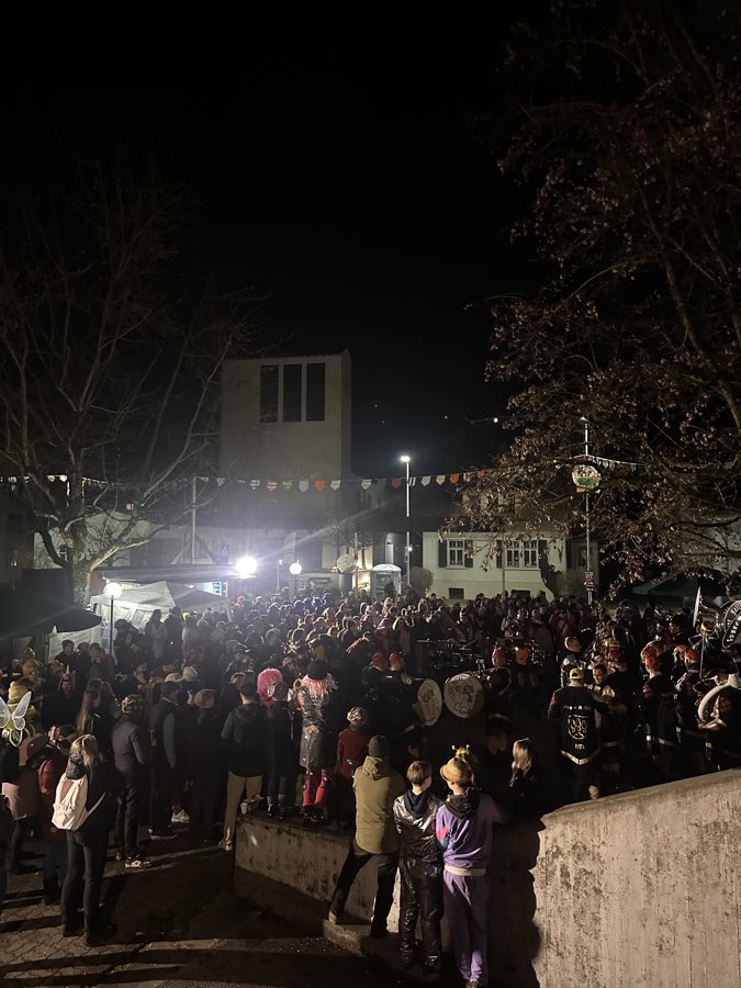 Dicht gefüllter Festplatz beim Häxechessel am Abend, Lichterketten über der Menge
