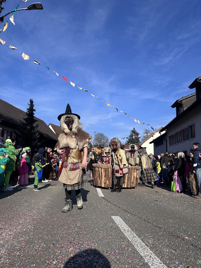 Häx mit Spitzhut führt die Gruppe durch die Strasse, dahinter weitere Häxe in Fell und Karostoff